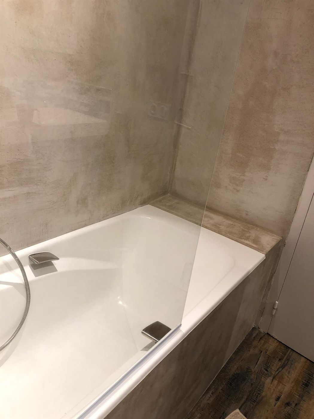 Baignoire encastrée entourée de béton ciré taupe