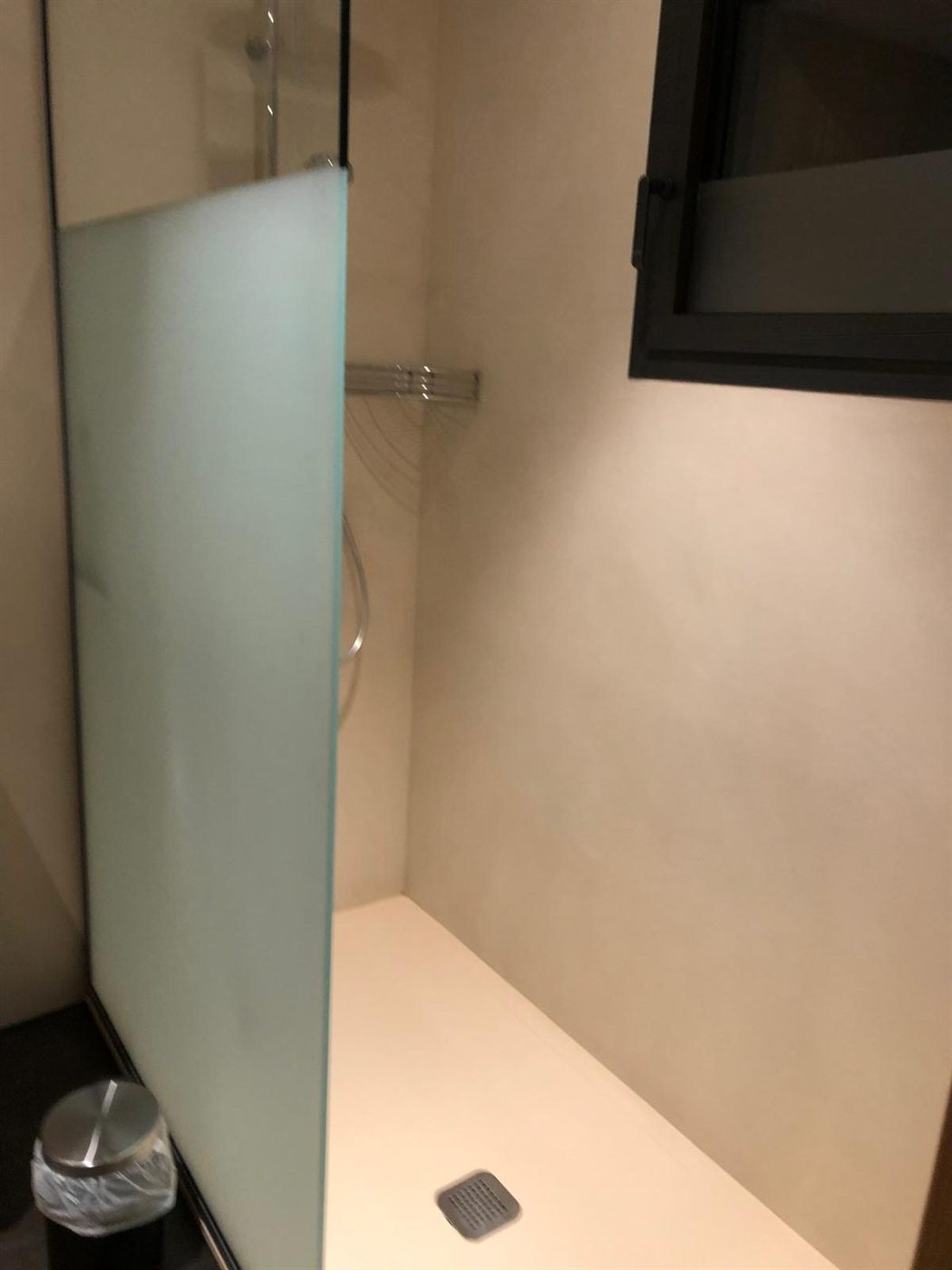Douche à l'italienne en béton ciré beige avec paroi en verre dépoli