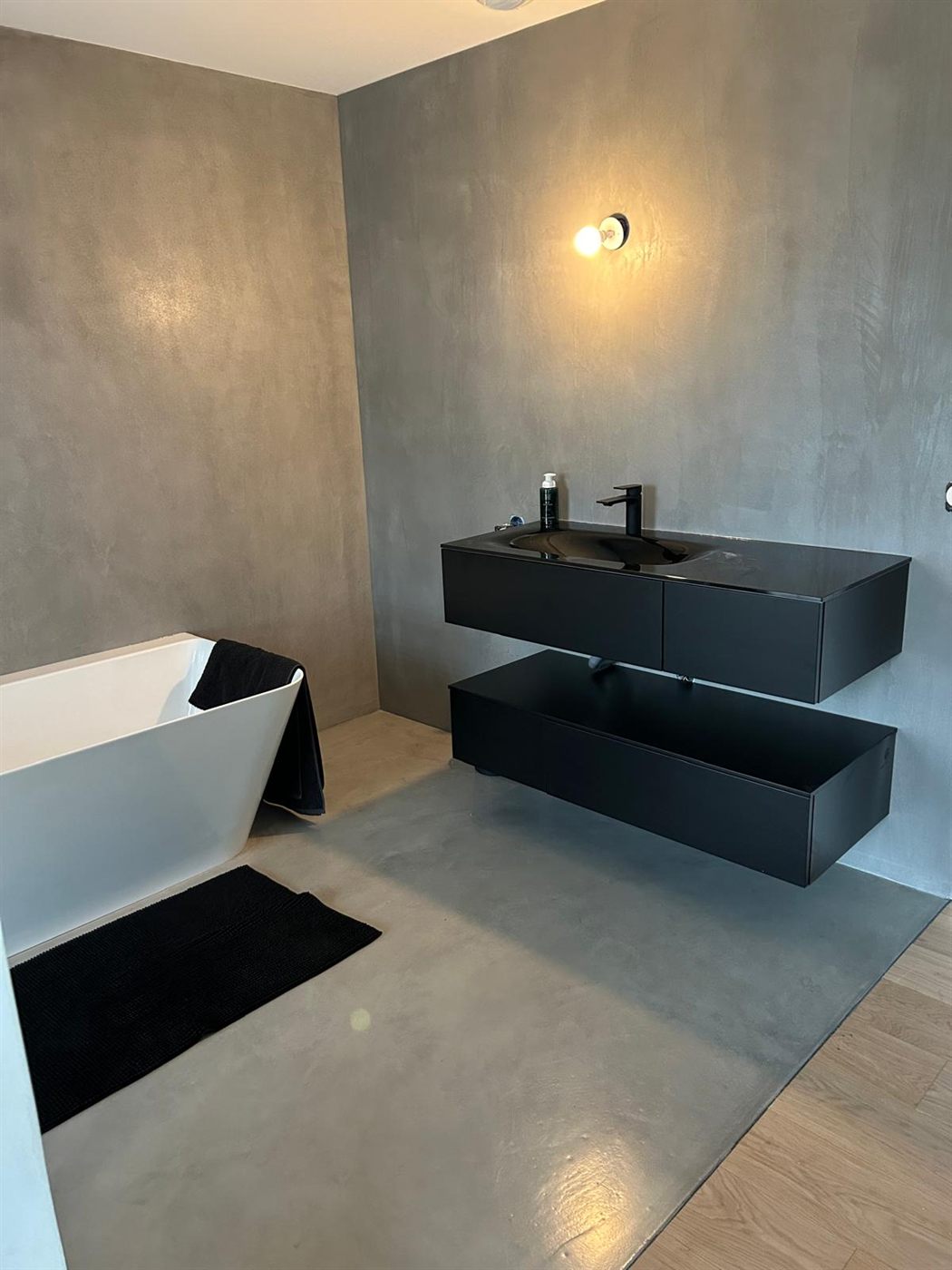 Salle de bain en béton ciré gris avec baignoire îlot, réalisée par IA Renov