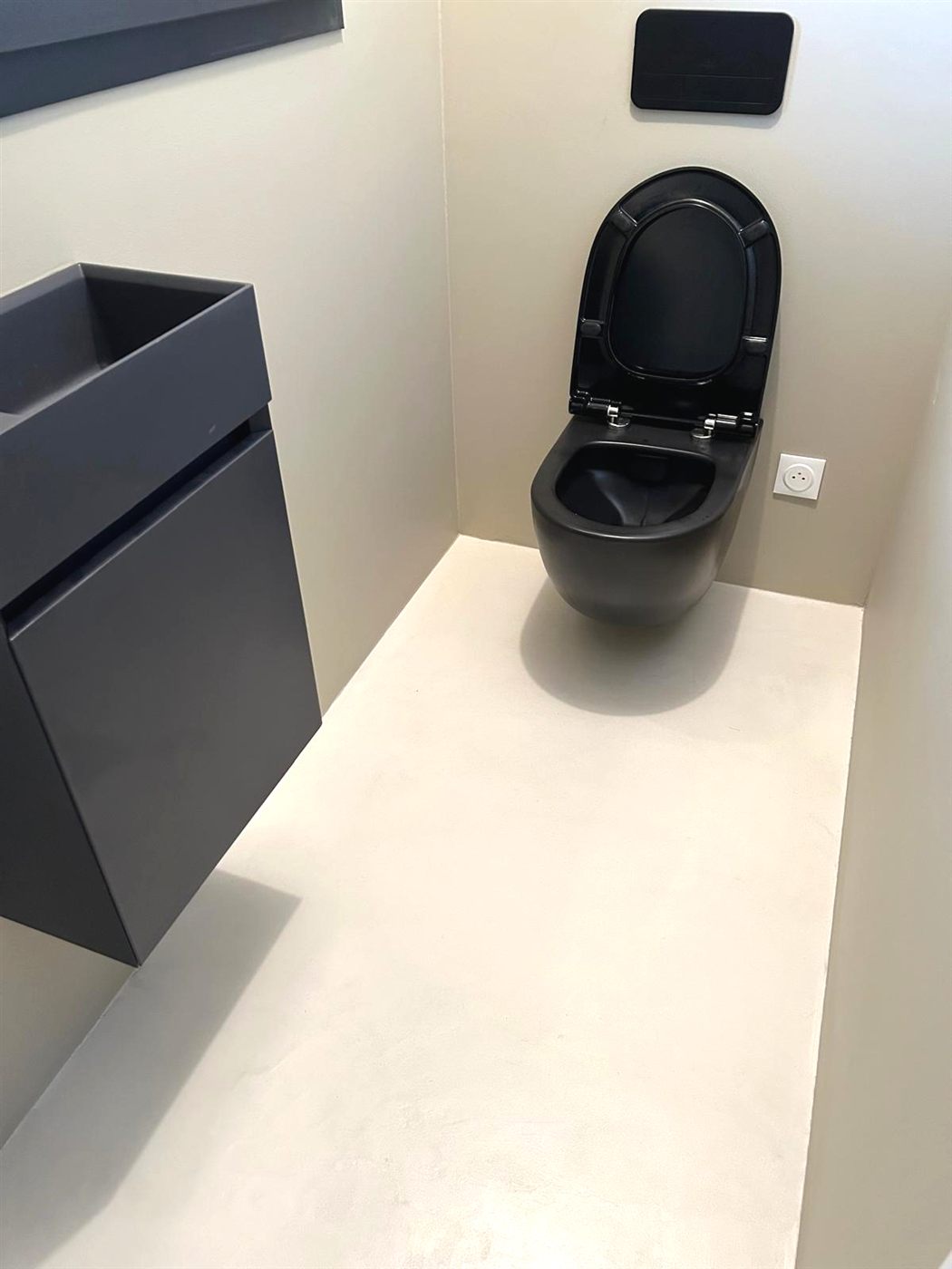 WC suspendu noir mat sur sol et murs en béton ciré crème